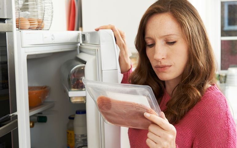 Concerned Woman Looking At Pre Packaged Meat