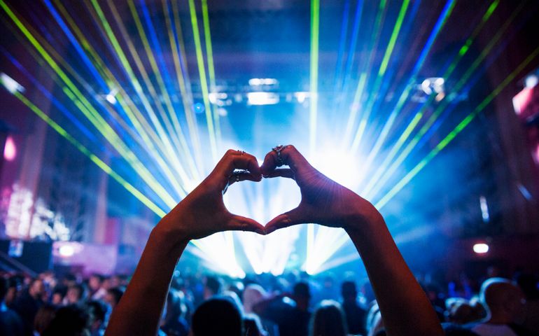 Woman making heart shape with hands at music event