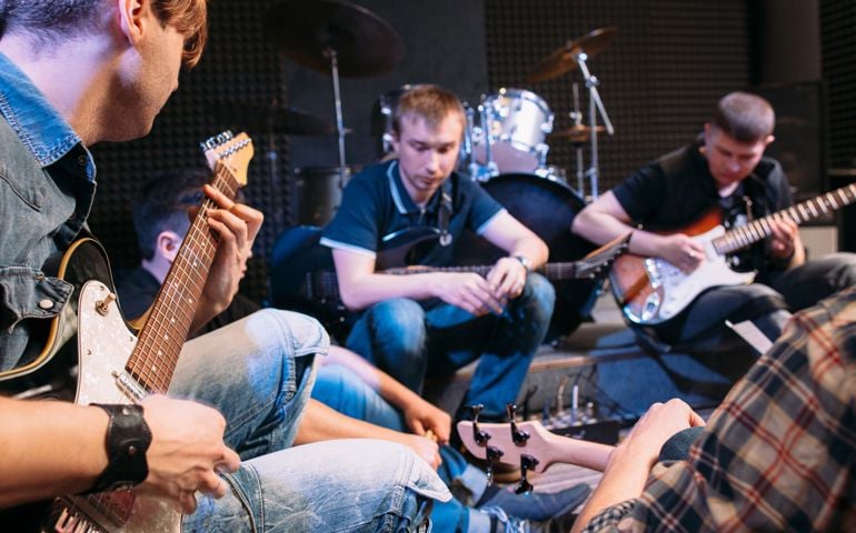 Band rehearsal before a live performance. Guitarists of music group sitting with their instruments and strum the guitar
