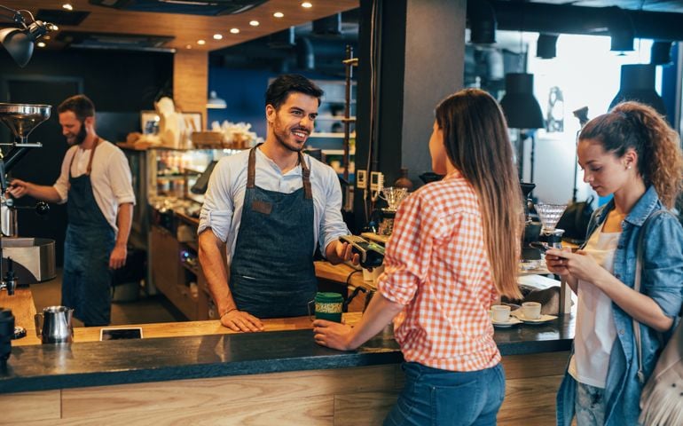 Customer making a contactless payment via credit card at a cafeteria.