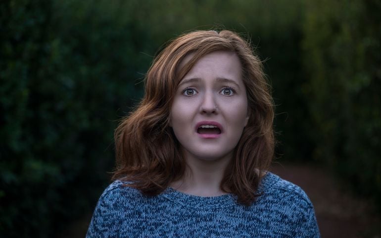 Portrait of shocked young woman looking at camera with negative facial expression