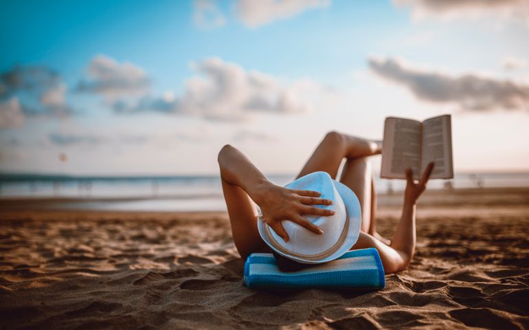 Female Reading and Enjoying Sunset on Beach by the Ocean