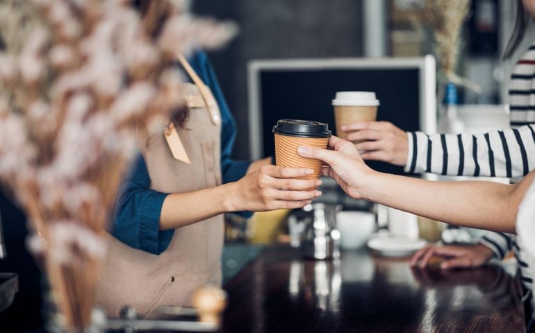 Barista served take away hot coffee cup to customer at counter bar in cafe restaurant,