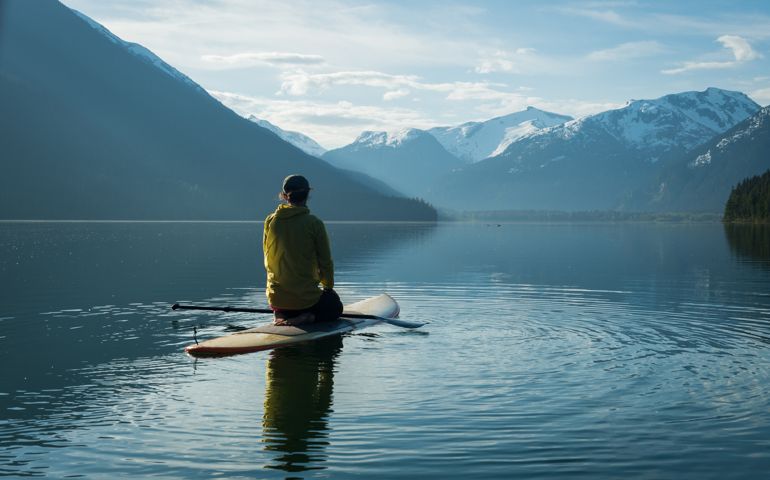 Woman stand up paddle boarding on a pristine mountain lake