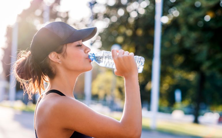 Photo of Sporty young woman drinking water