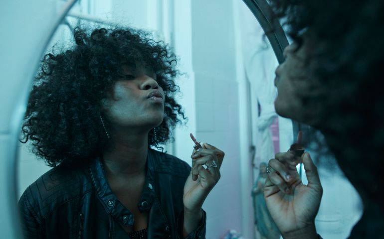 Young women doing make-up in the bathroom mirror at pre-party