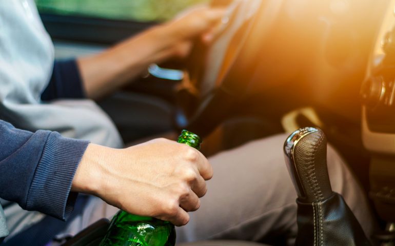 Drinking and driving ,man drinking alcohol and using mobile phone while driving car ,concept drive safely while using a cell phone or drunk alcohol