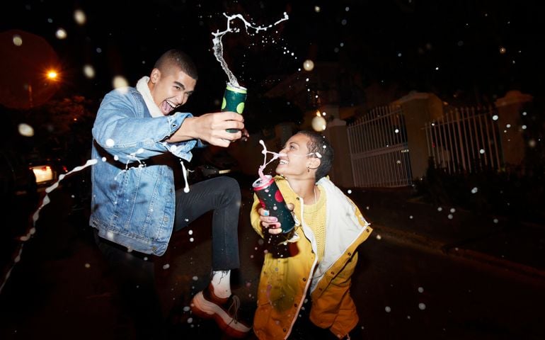 Cheerful male and female splashing drink
