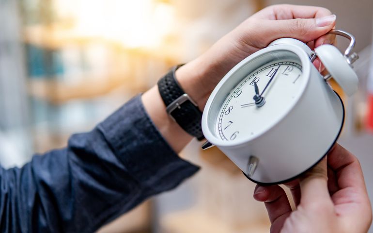 Male hand adjusting the time on white clock