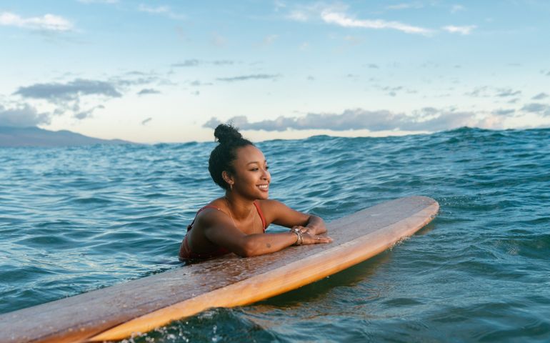 Young woman resting on her surfboard waiting for a wave
