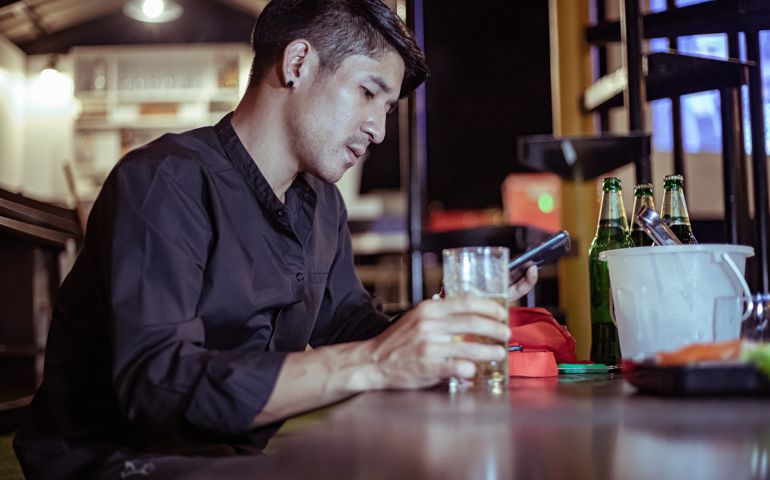 Stressed drunk man sitting alone with glass of beer in bar