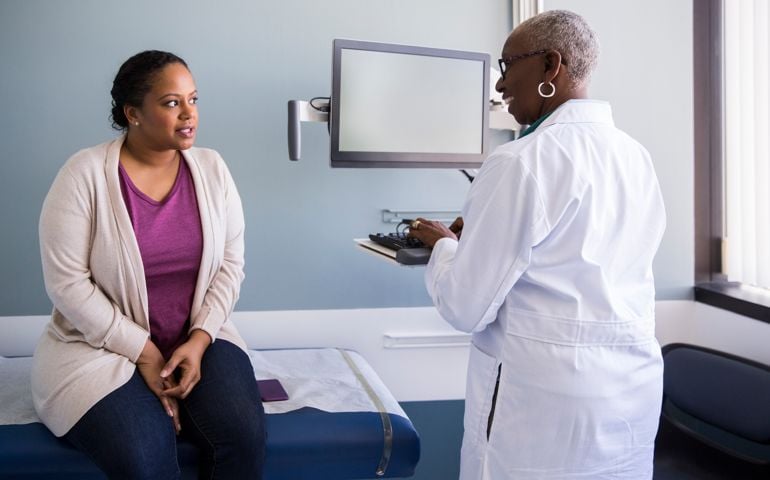 Smiling senior doctor talking to patient in hospital