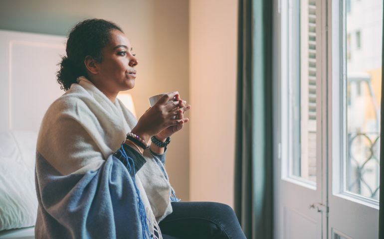 woman with a blanket looking out window
