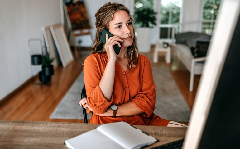 Young woman talking on smart phone at home office