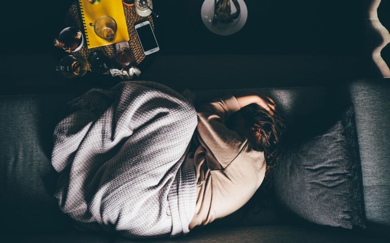Worried young woman lying on sofa at home.