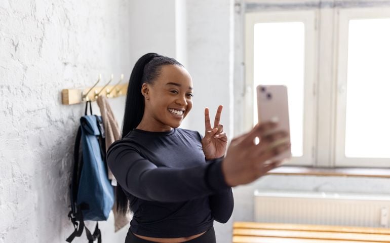 Young African woman taking selfies in the dressing room at gym