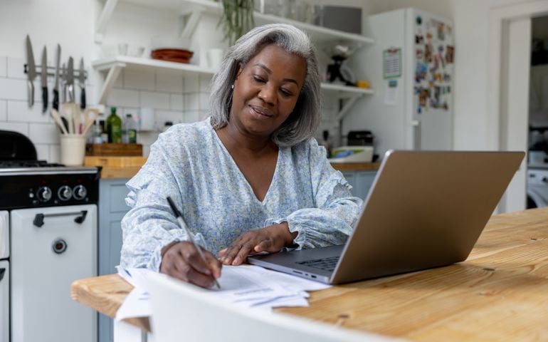 Mature woman at home taking classes online using her laptop