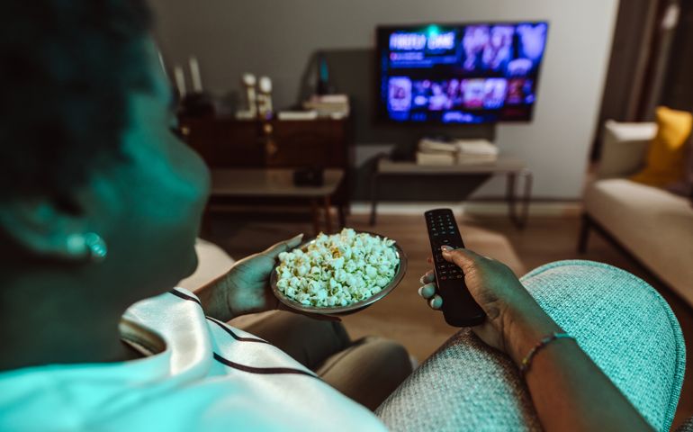 woman watching favorite TV show and eating popcorn at home.