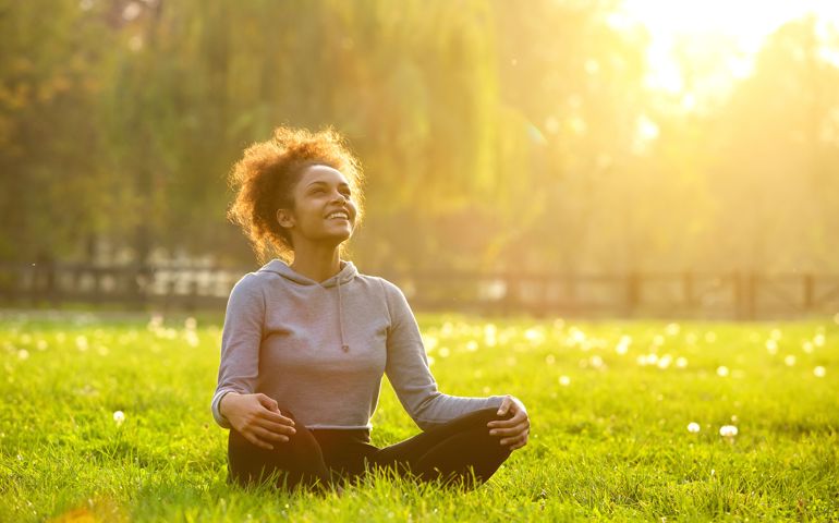 Happy young woman sitting in yoga position