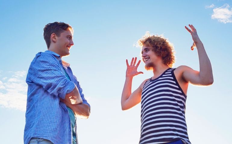 Two male friends enjoying conversation in sunlight