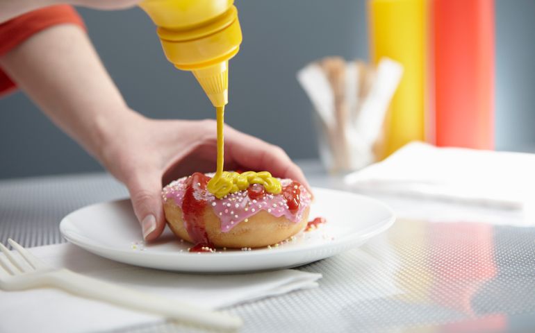 Woman squirting donut with ketchup and mustard