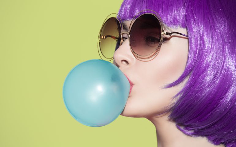 woman portrait blowing a blue bubble chewing gum