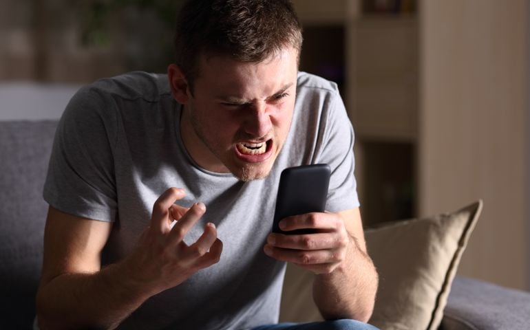 Angry man with a mobile phone at home
