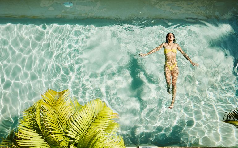 Overhead view of woman floating on her back in pool at outdoor spa