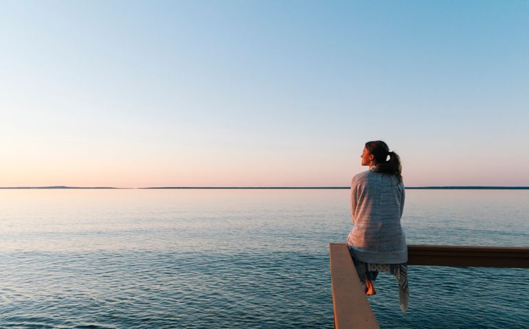Young woman sitting on edge looks out at view
