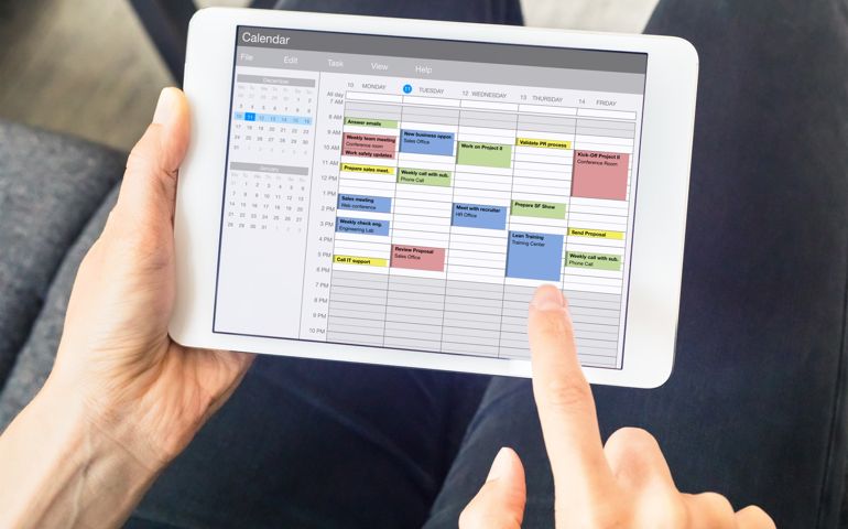 Calendar app on tablet computer with planning of the week with appointments, events, tasks, and meeting. Hands holding device, time management concept, organization of working hours planner, schedule