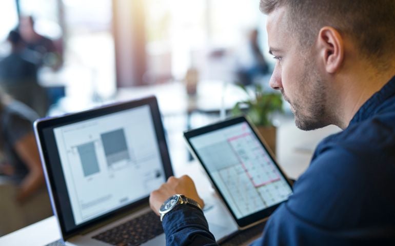 Business man looking and analyzing projects on his laptop computer and tablet.