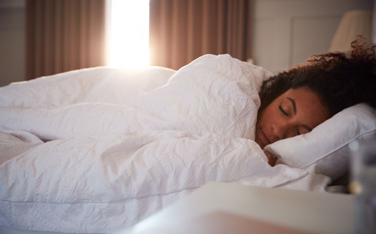Peaceful Woman Asleep In Bed As Day Break Through Curtains