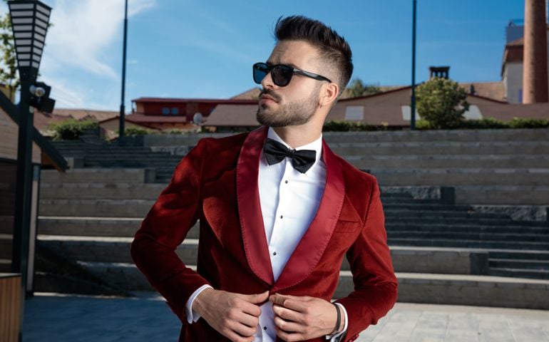 confident young elegant man arranging coat outdoor