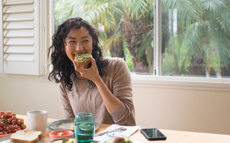 Young woman eating avocado toast at home