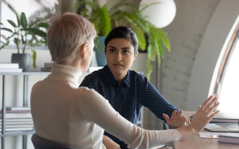 Indian and caucasian businesswomen negotiating sit at desk in office