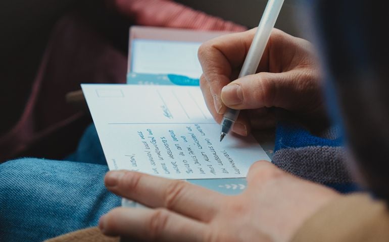 Hand of Person Writing Postcard
