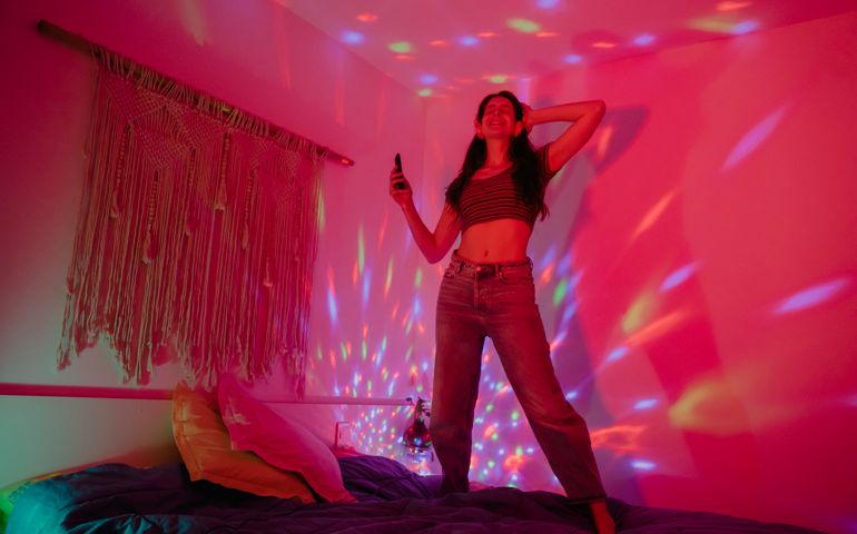 Cheerful woman dancing while partying in bedroom