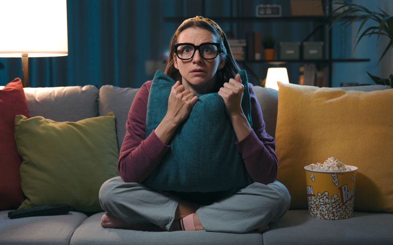 Woman watching a horror movie at home
