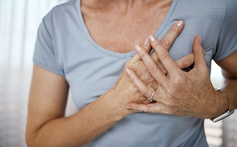 Cropped closeup of an unrecognizable woman experiencing cardiac discomfort at home