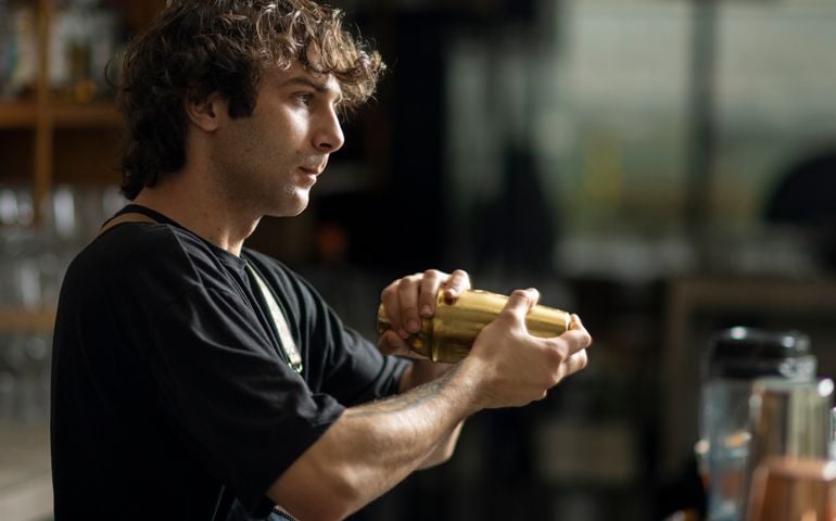 Young bartender making a cocktail, shaking a cocktail shaker