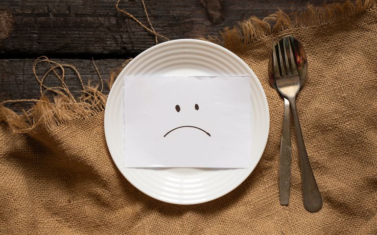 a sad smiley is drawn on paper lies on a white plate, on a wooden table and on a brown tablecloth, sadness and depression