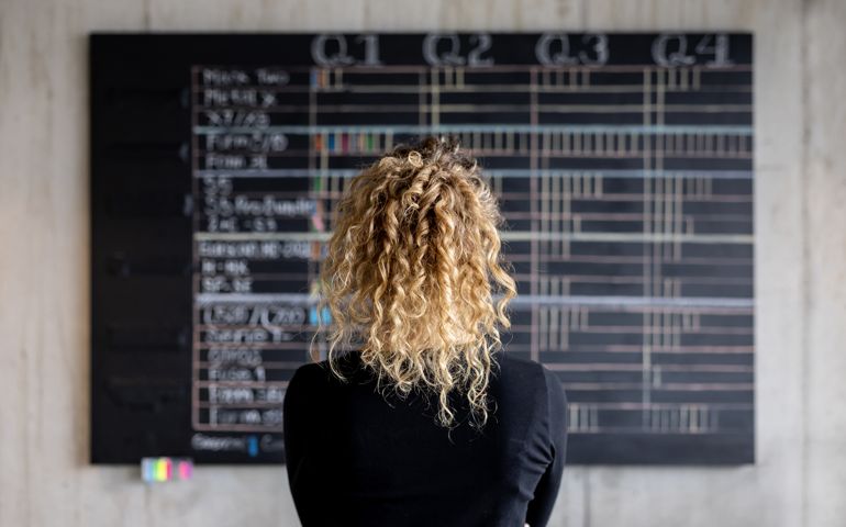 Business woman looking at the project management calendar in her office
