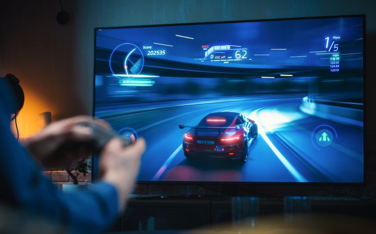 Close Up on Man's Hands at Home, Sitting on a Couch in Stylish Loft Apartment and Playing Arcade Car Video Games on Console. Male Using Controller to Play Street Racing Drift Simulator.