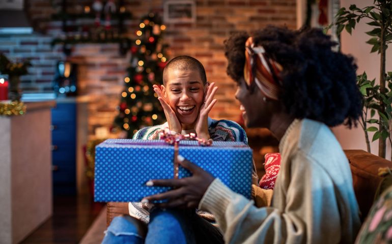 Young female couple gifting each other presents on Christmas eve
