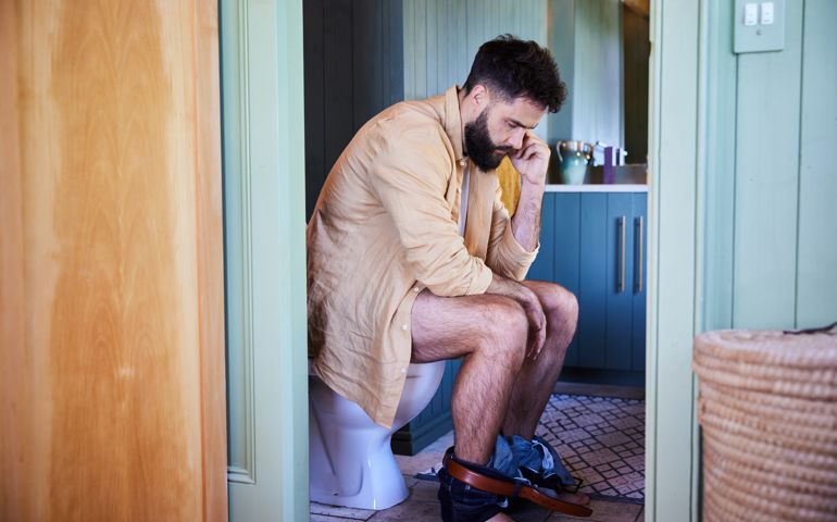Young man sitting on a toilet and going to the bathroom