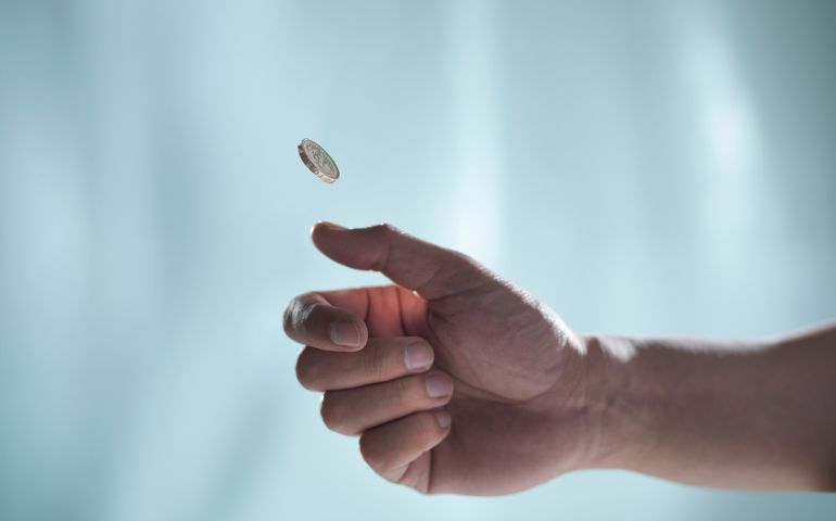 Man flipping one pound coin, pounds sterling
