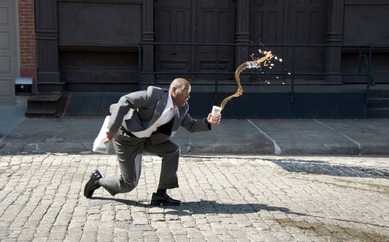 Businessman outdoors, spilling cup of coffee on pavement, side view