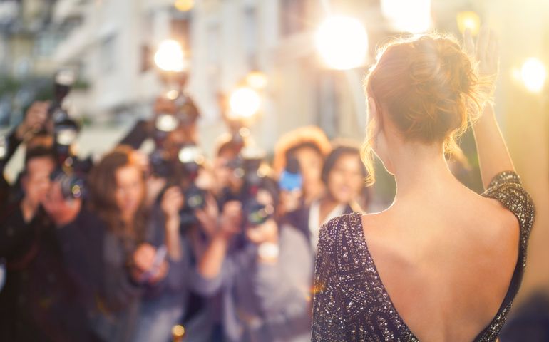 Celebrity waving at paparazzi photographers at event