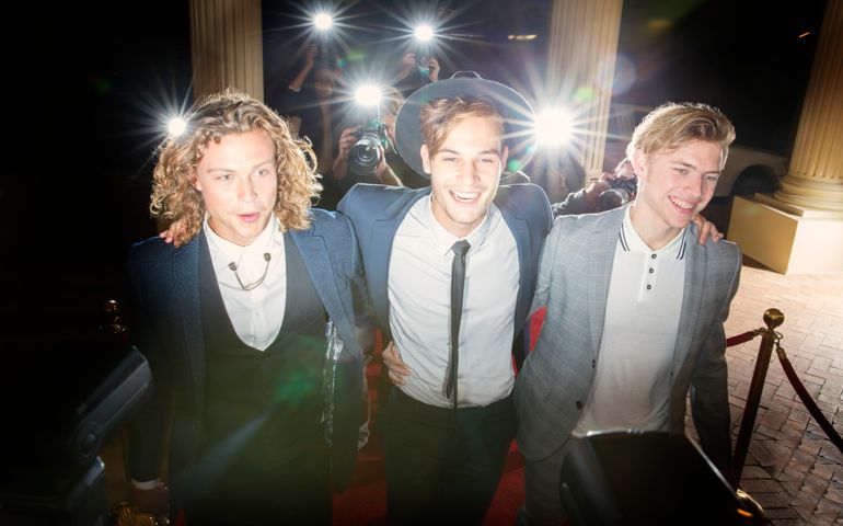 Smiling celebrities walking in a row at red carpet event