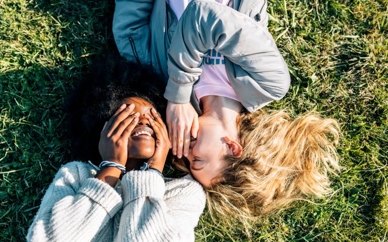 Two best friends telling secrets lying in the grass
